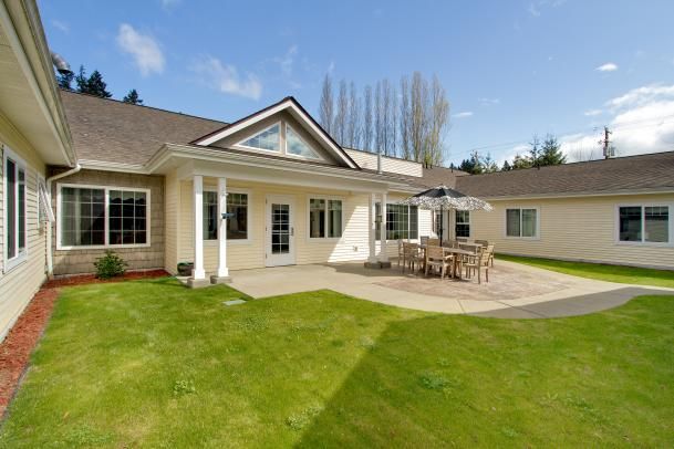 A spacious backyard with a patio and outdoor furniture on a sunny day.