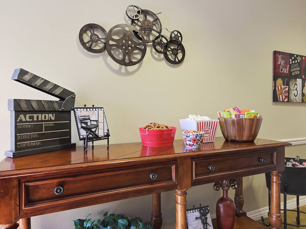A stylish wooden desk decorated with a film reel sculpture, snacks, and other decorative items.