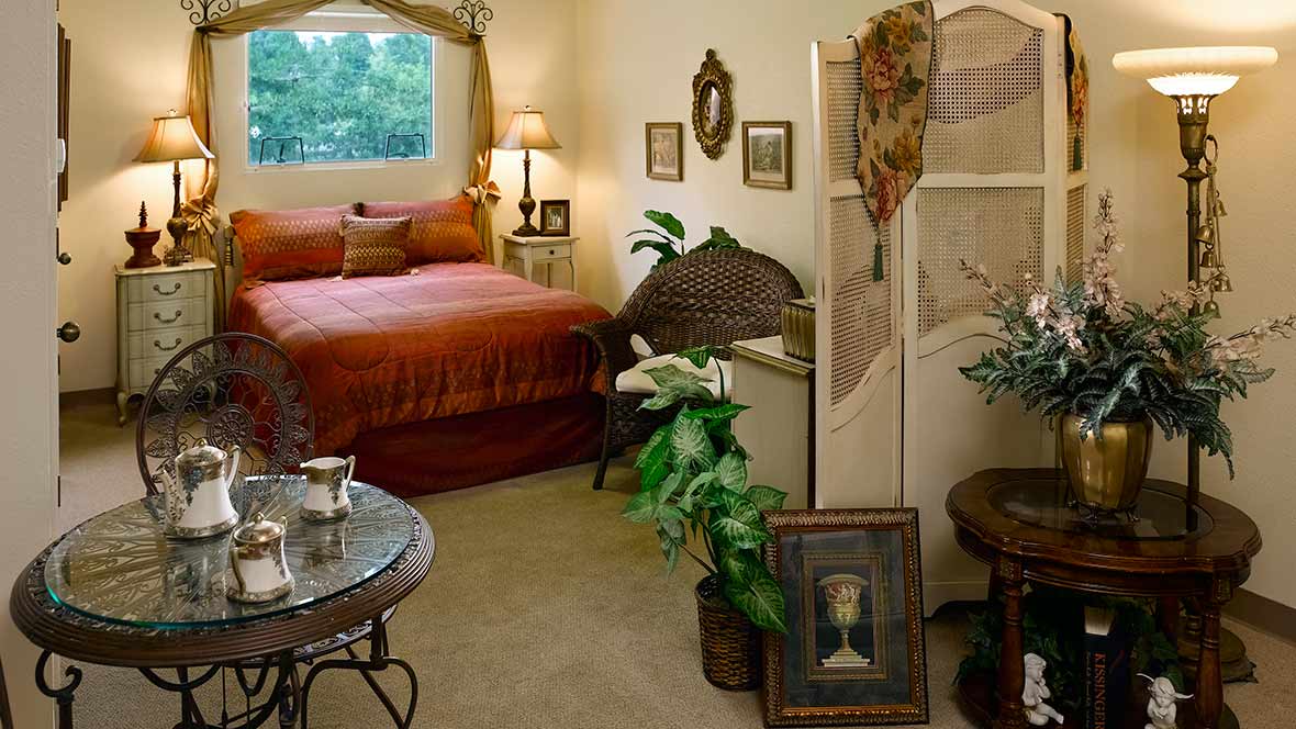 A cozy bedroom with vintage decor and a variety of plants, featuring a comfortable bed and artwork on the walls.