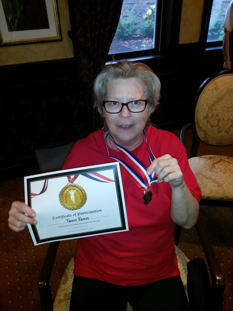 A person holding a certificate and wearing a medal, celebrating an achievement.
