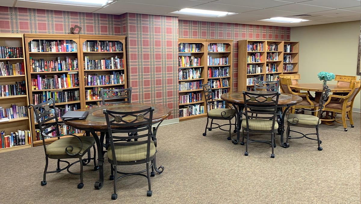 A cozy library reading area with tables and bookshelves filled with books.