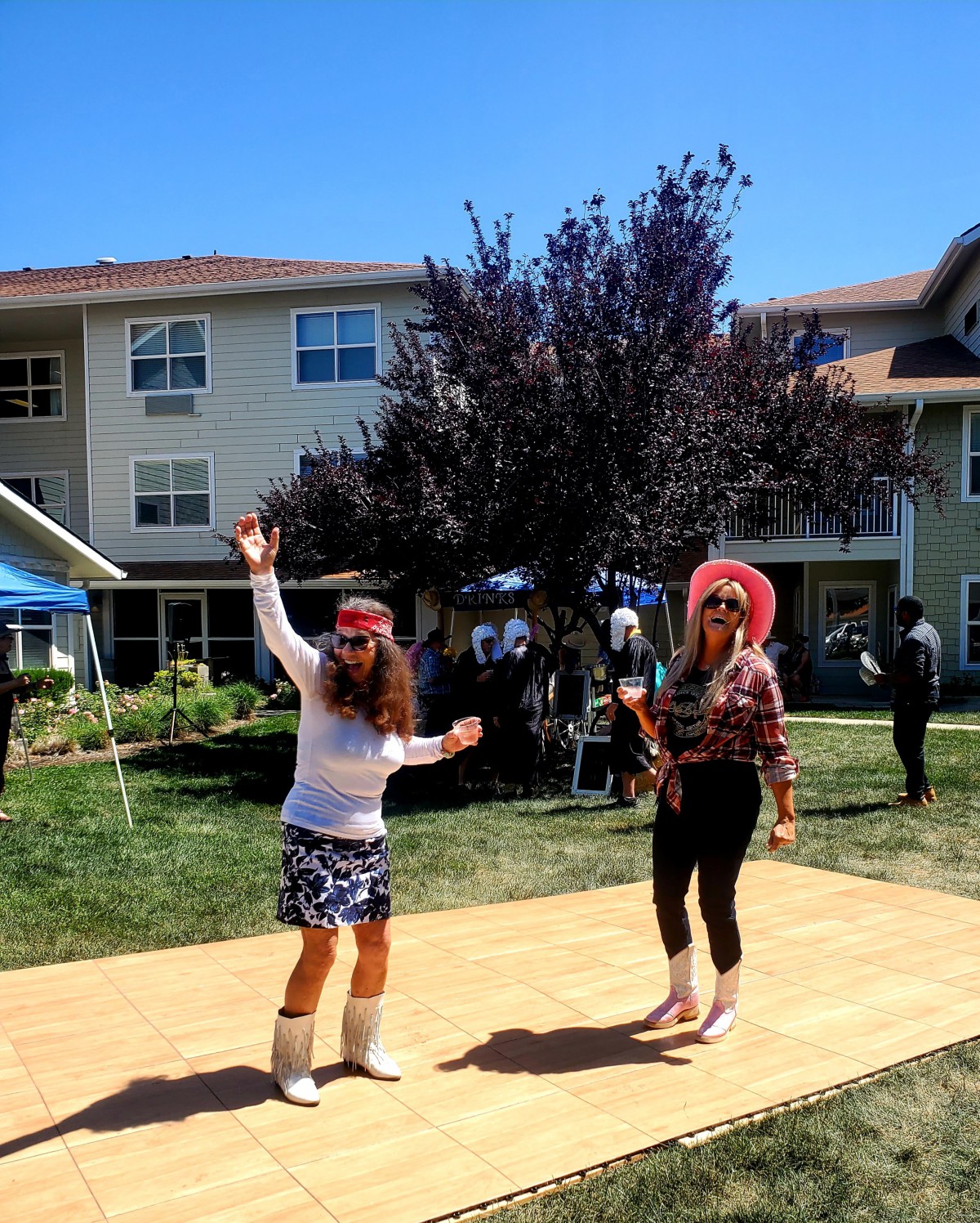 Two people dancing outdoors in costumes during a sunny day.