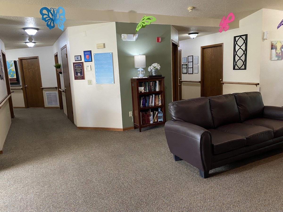 A cozy office waiting area with a sofa and a bookshelf.