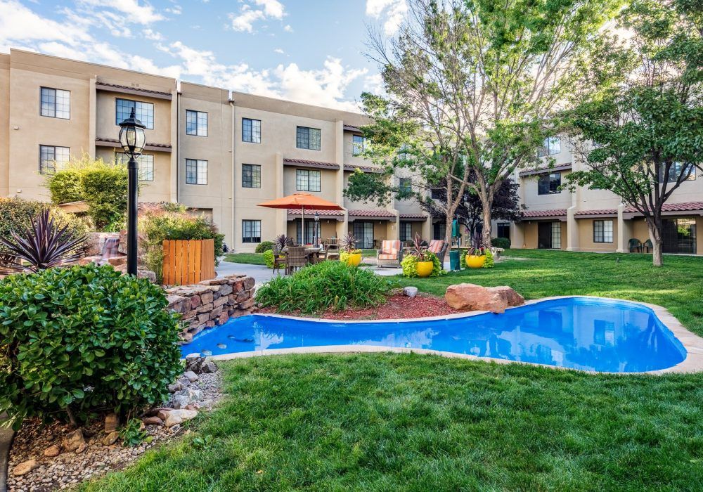 A serene view of an apartment complex with well-maintained gardens and lush greenery.