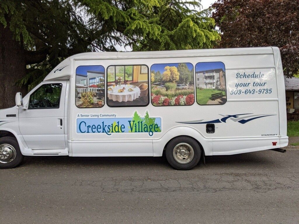 A bus with a vehicle wrap advertising Creekside Village, a retirement community.