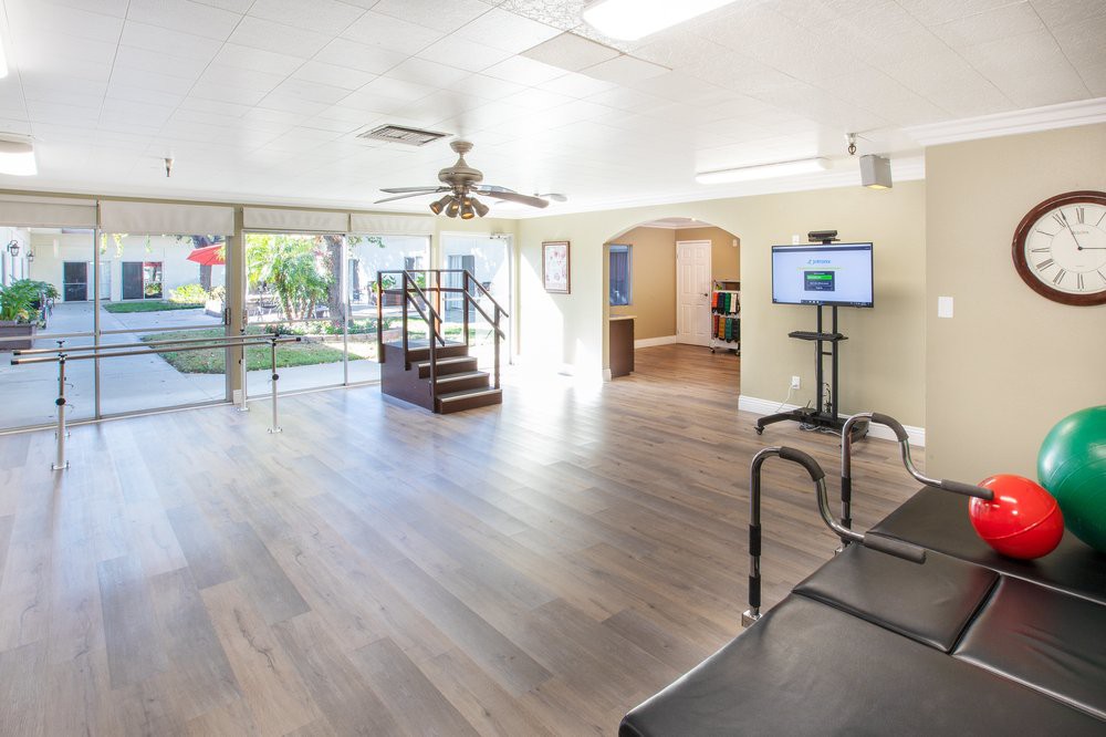 Spacious gym with wood flooring and bright lighting, featuring exercise equipment.