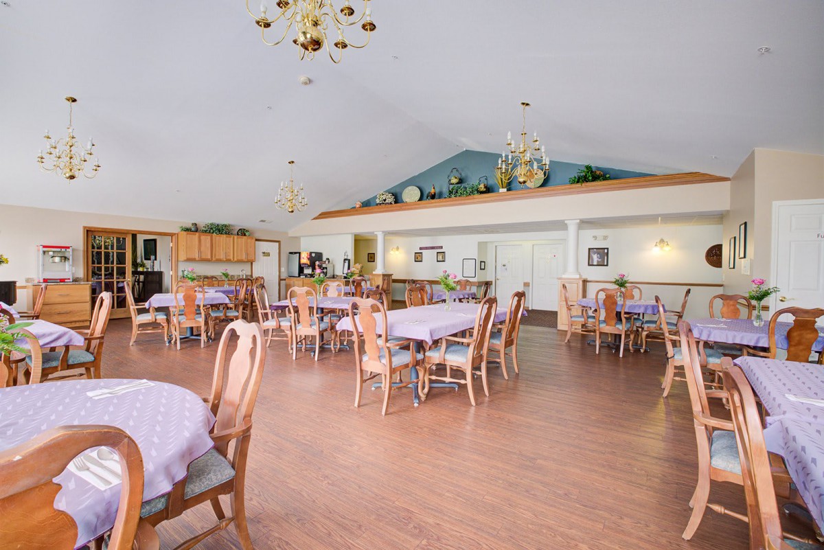 A spacious dining area with neatly arranged tables and chairs, featuring elegant chandeliers and decor.