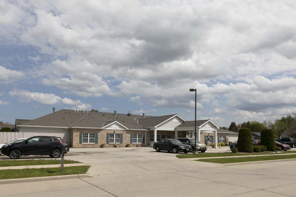 A suburban residential building with a parking lot under a cloudy sky.