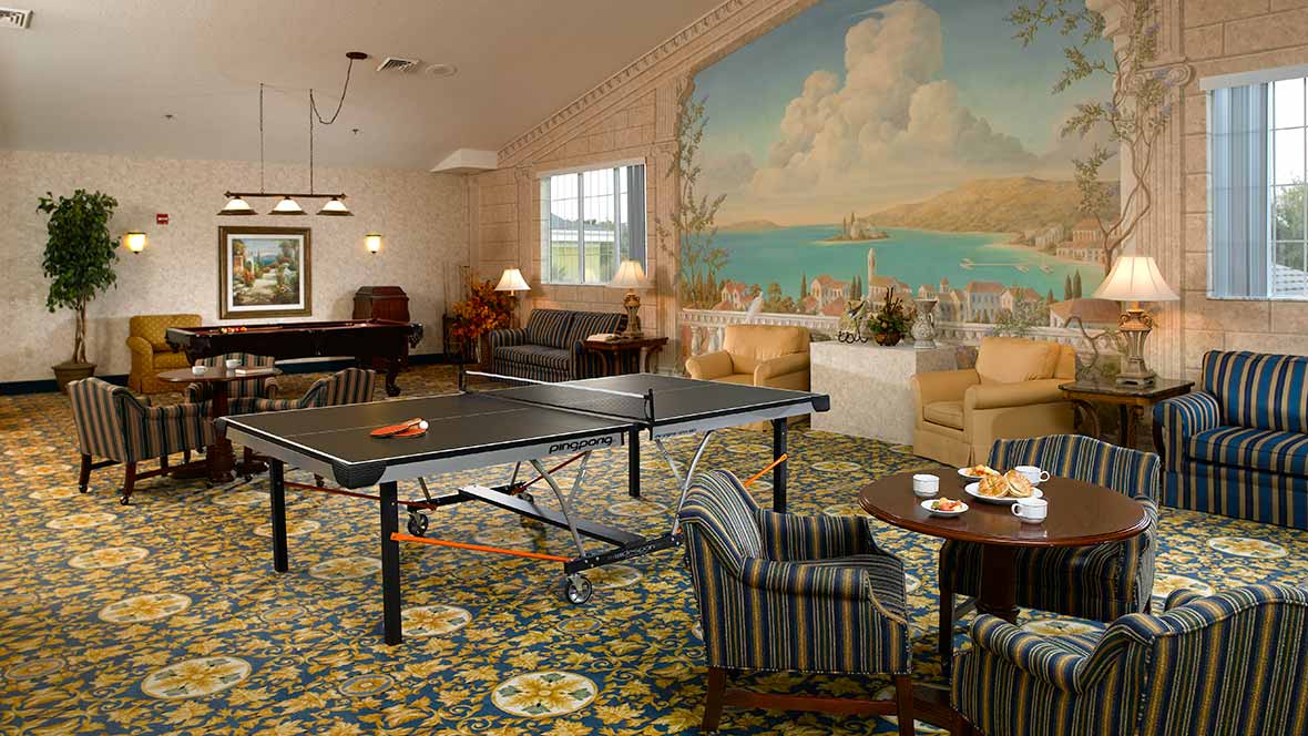 A cozy game room featuring a table tennis setup, comfortable seating, and a large mural on the wall.