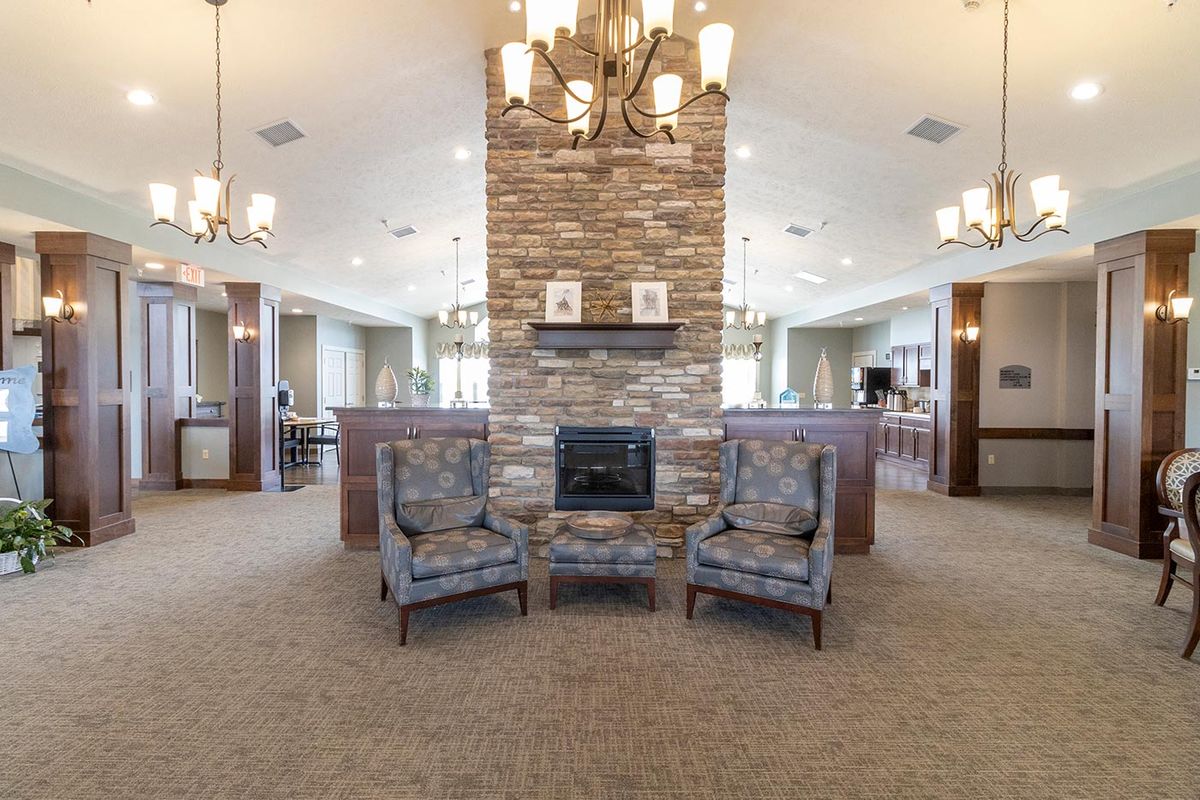 A cozy lounge area featuring two chairs and a stone fireplace, illuminated by elegant chandeliers.