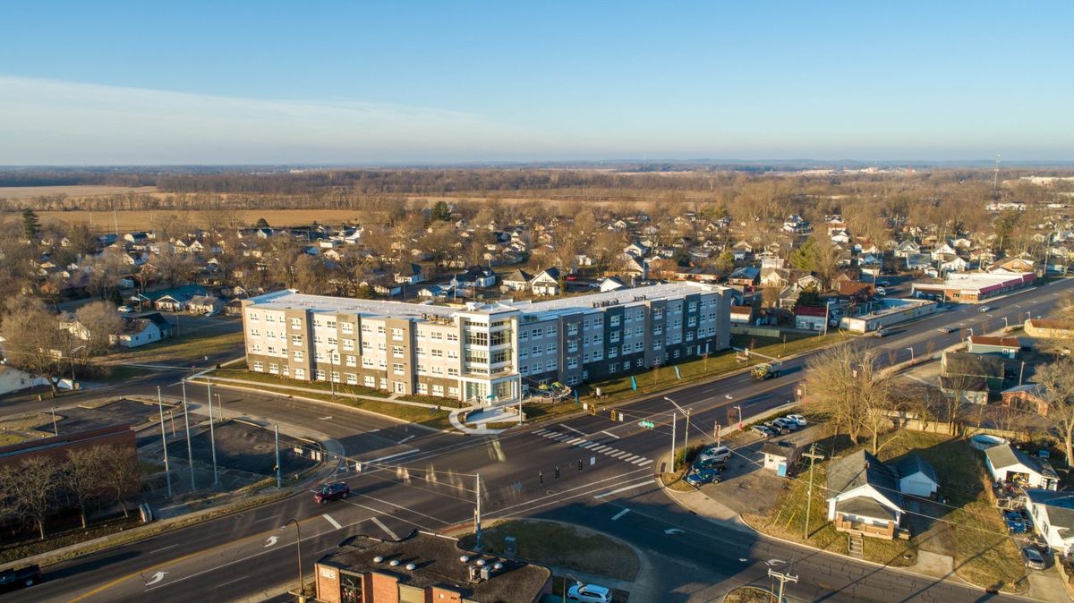 An aerial view of an urban intersection with a modern building and surrounding neighborhood.
