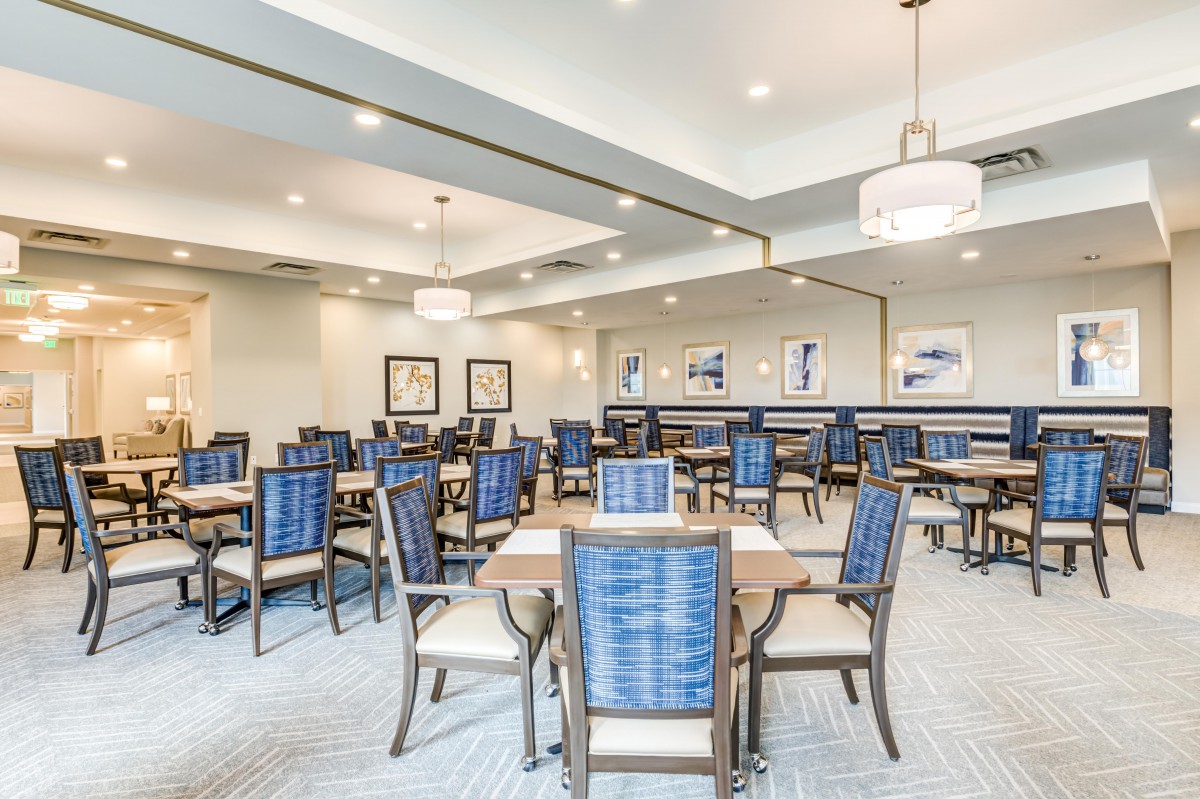 A modern dining room with neatly arranged tables and chairs under bright ceiling lights.