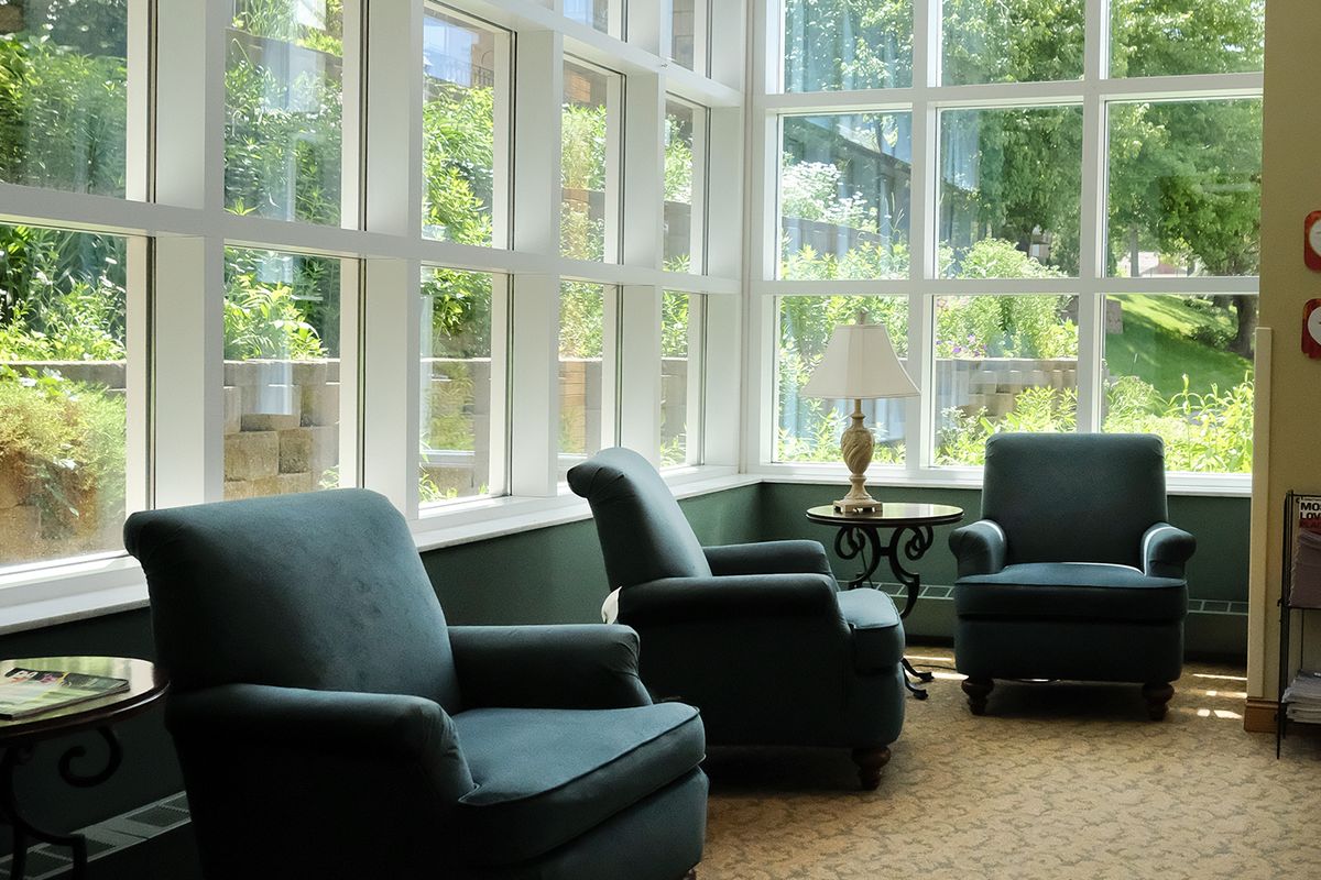 A cozy living room with armchairs and large windows letting in natural light.