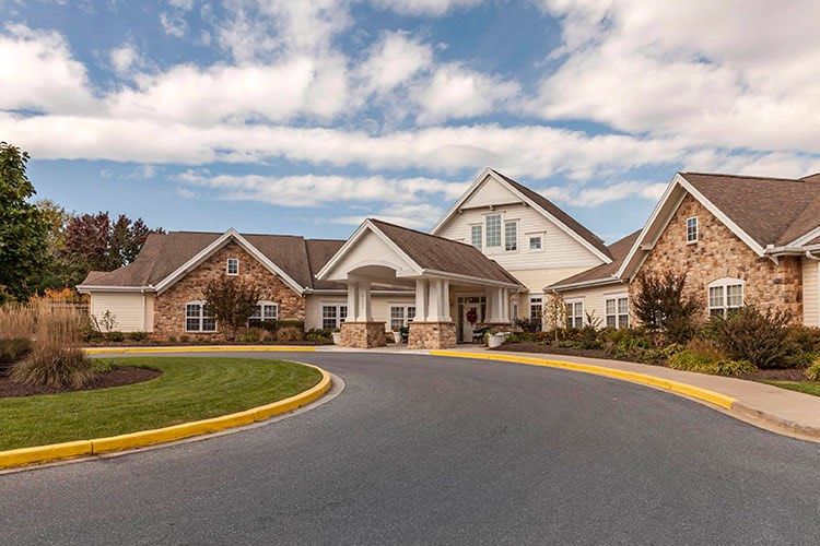 A picturesque residential building with a circular driveway under a partly cloudy sky.