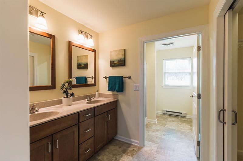A modern bathroom with double sinks and wooden cabinets.