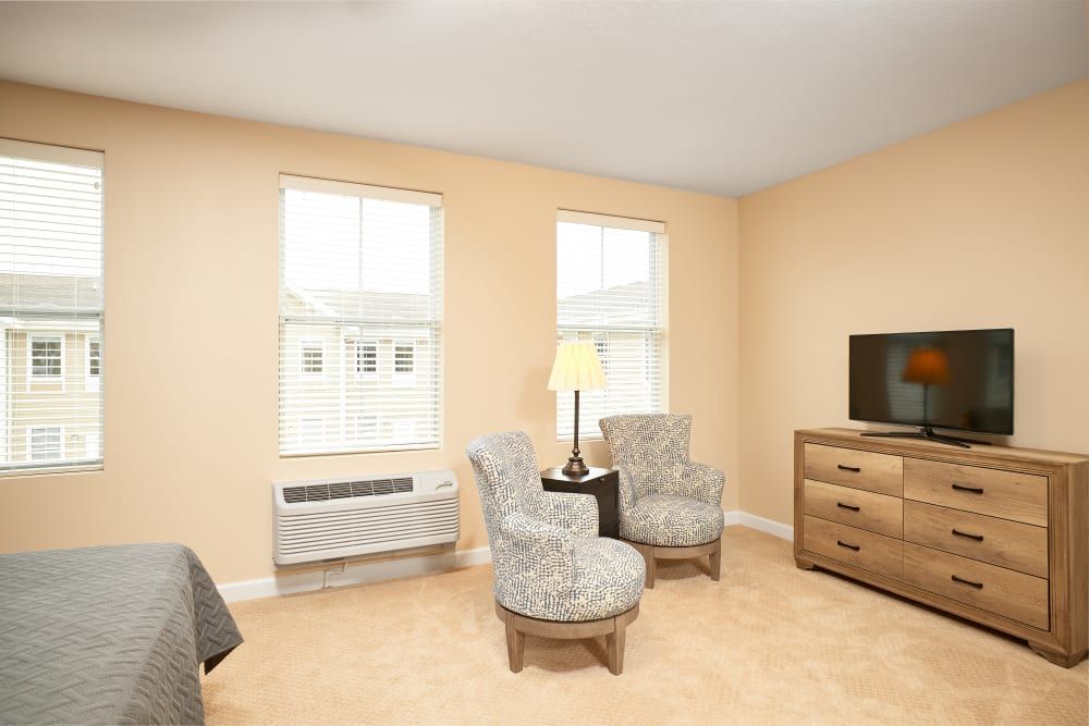 A cozy living room with two chairs, a lamp, and a television.