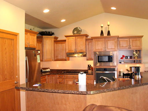 A modern kitchen featuring wooden cabinetry and a spacious granite countertop.
