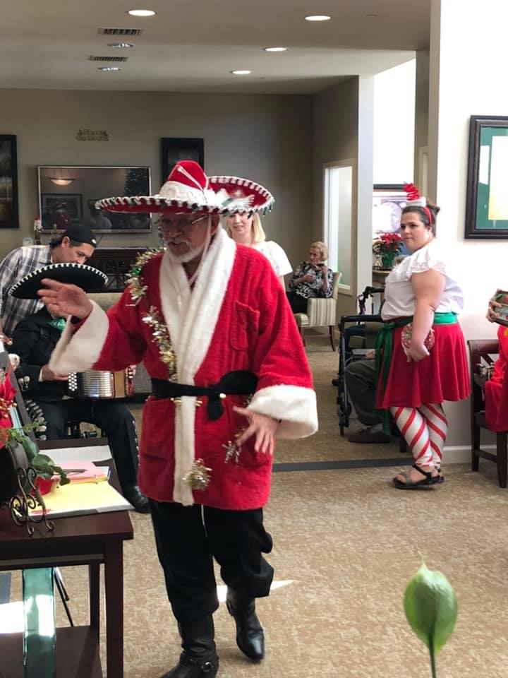 A person dressed as Santa Claus wearing a sombrero, participating in a festive indoor event.