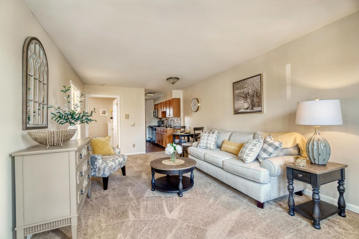 A cozy and bright living room with a sofa, armchair, coffee table, and decorative accents.