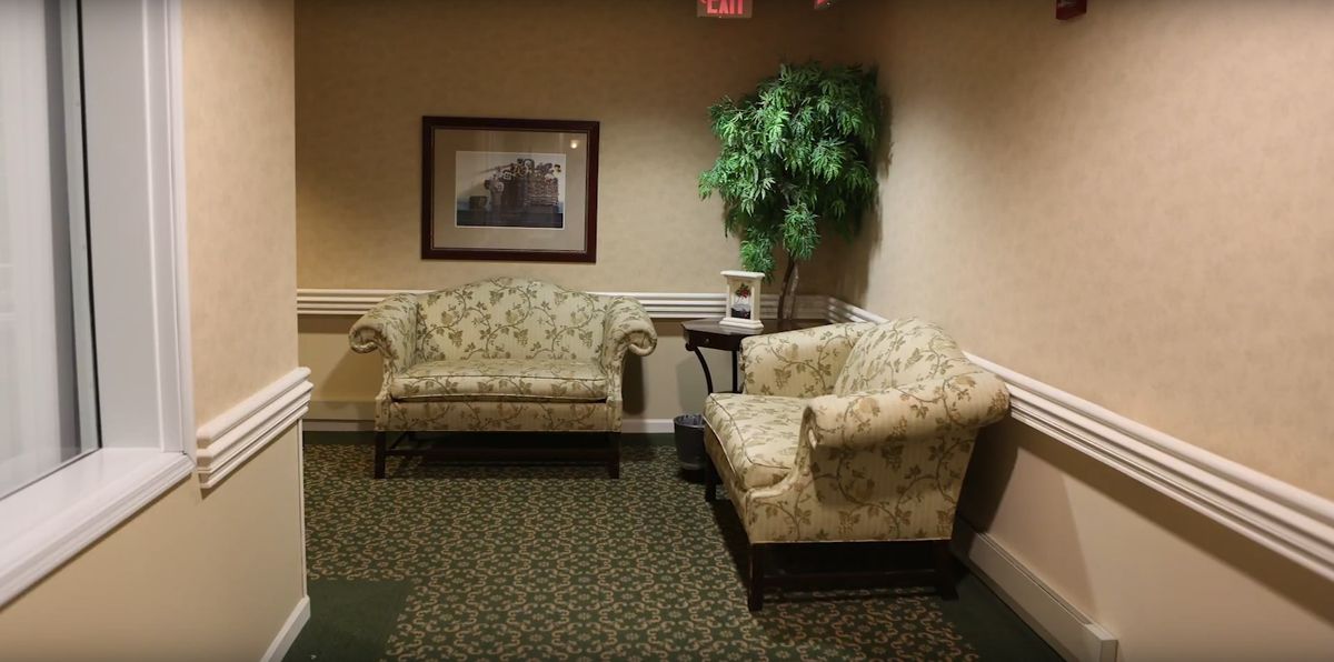 A cozy lobby area with floral-patterned sofas and a potted plant.