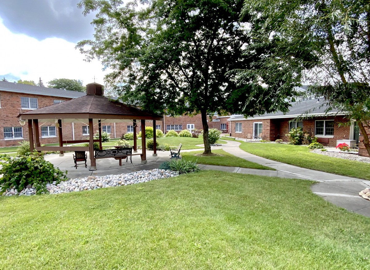 A peaceful garden area featuring a gazebo, pathways, and lush greenery.