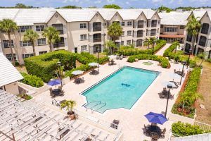 Aerial view of a hotel resort featuring a large swimming pool surrounded by lounge chairs and umbrellas.
