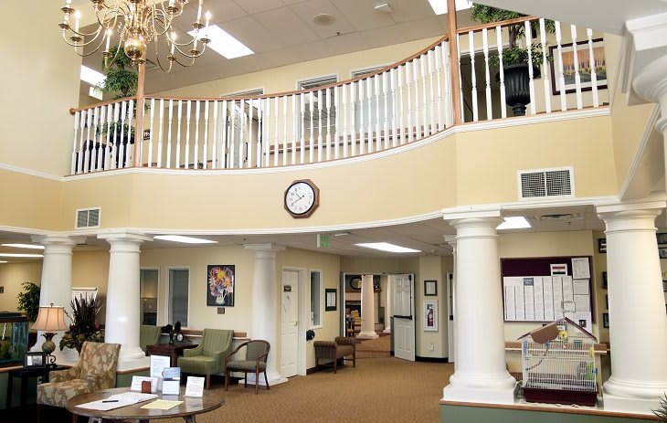 A spacious lobby with a balcony, featuring comfortable seating and classic columns.