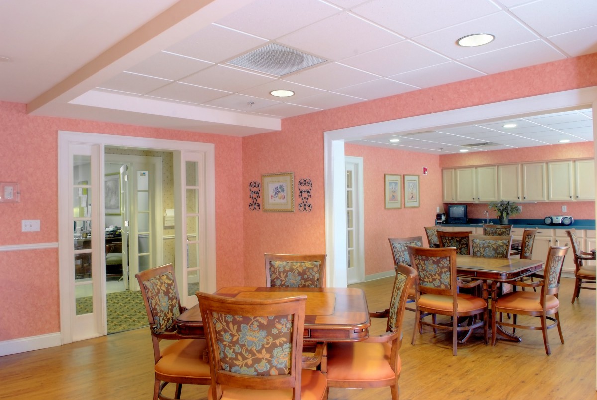 A cozy dining area with wooden furniture and vibrant wall colors, adjacent to a kitchen space.