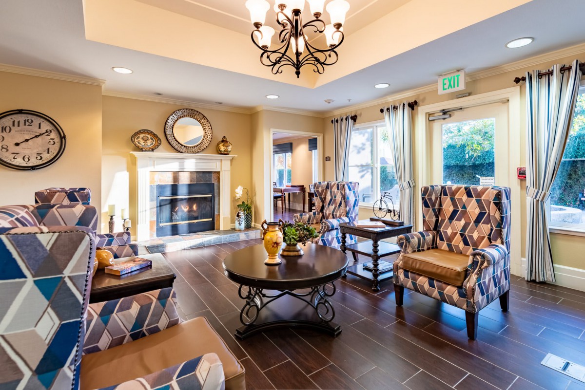A cozy living room with traditional decor featuring a fireplace, chandelier, and comfortable seating.