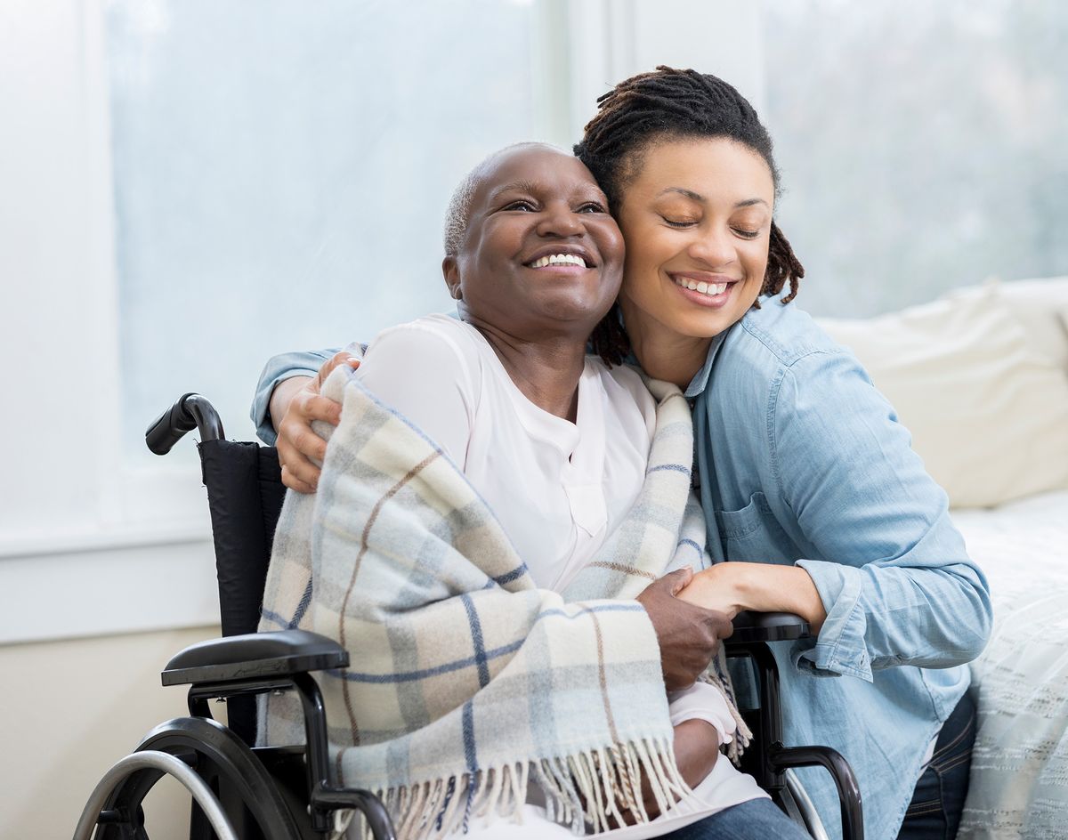 A joyful moment shared between two people, one in a wheelchair and the other embracing them warmly.