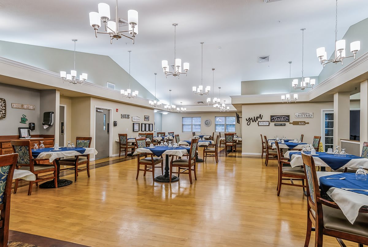 A spacious dining room with neatly arranged tables and elegant chandeliers.