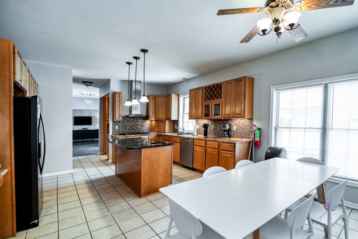 A modern kitchen with wooden cabinets, an island, and a dining area.