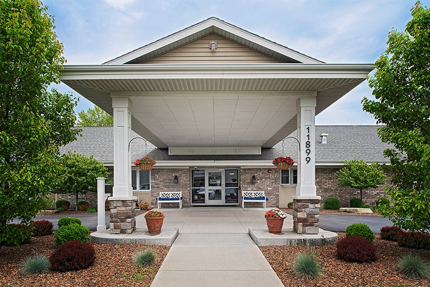 A welcoming entrance to a building with an awning and potted plants.