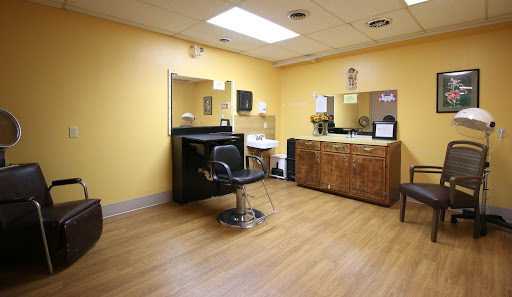 A cozy salon space featuring a styling chair and wooden cabinets against a cheerful yellow backdrop.