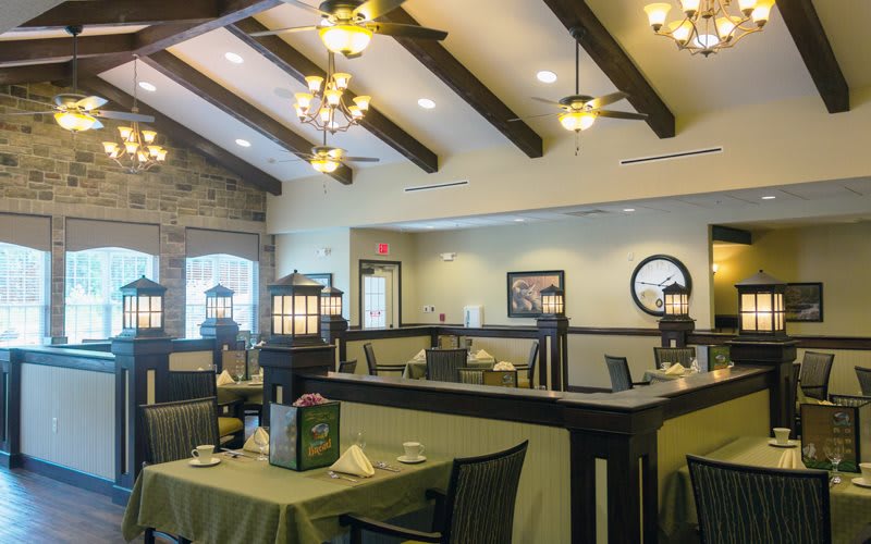 A cozy restaurant interior with wooden ceiling beams and elegant chandeliers.