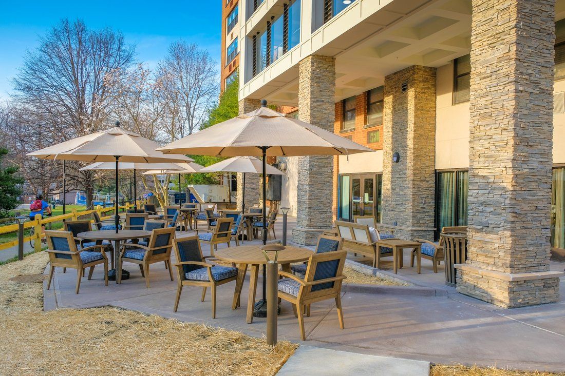 An inviting outdoor patio area with tables, chairs, and umbrellas next to a building.