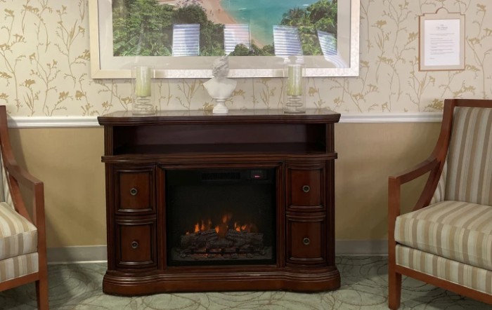 A traditional wooden electric fireplace in a cozy living room setting.
