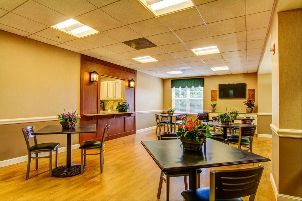 A cozy dining area with tables, chairs, and plants under warm lighting.