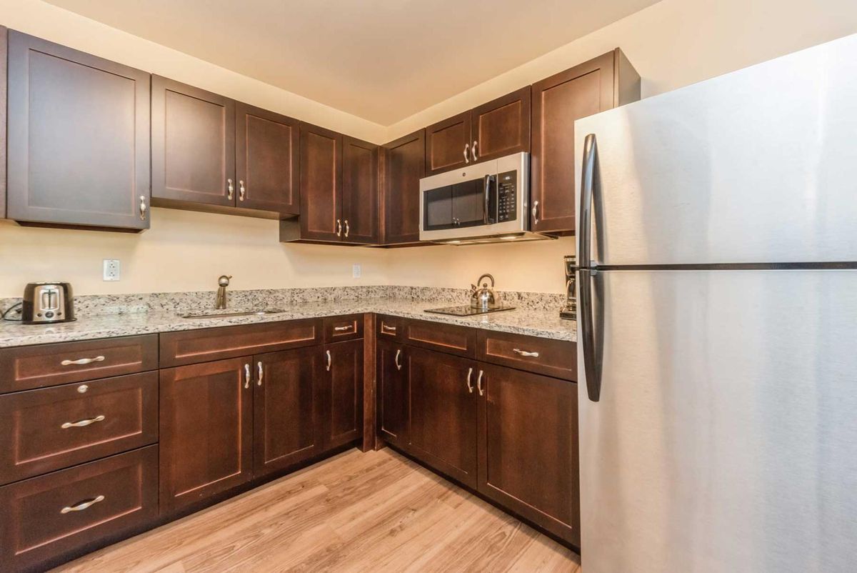 A modern kitchen with dark wood cabinets and stainless steel appliances.