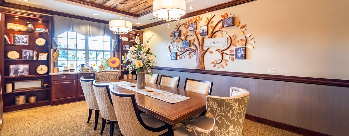 An elegantly designed dining room featuring a wooden table, upholstered chairs, and a family tree wall art.