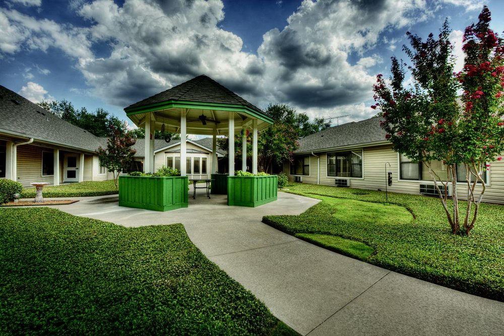 A vibrant green gazebo in a park setting under a cloudy sky.