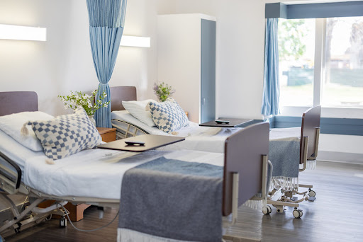 A well-lit and modern hospital patient room featuring two beds, clean linens, and a welcoming atmosphere.