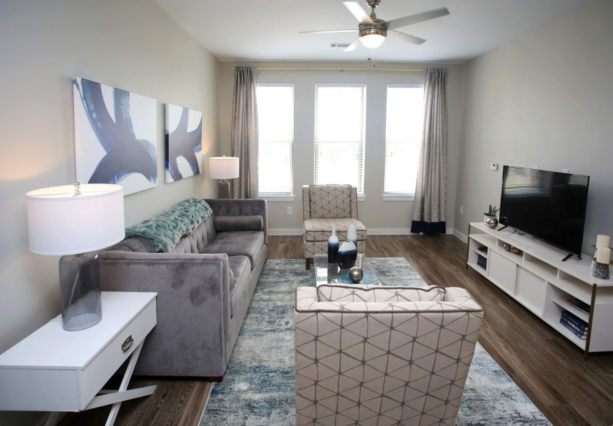 A modern living room with contemporary furniture, featuring a sofa, armchair, coffee table, and a television.