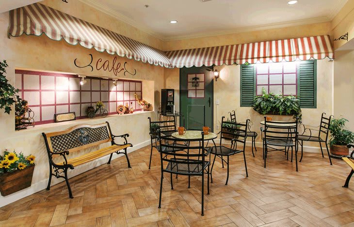 A cozy indoor cafe with a charming seating area, featuring tables and chairs under a decorative awning.