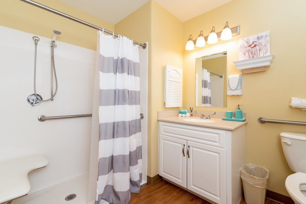 A neatly organized bathroom with a striped shower curtain and a well-lit vanity area.