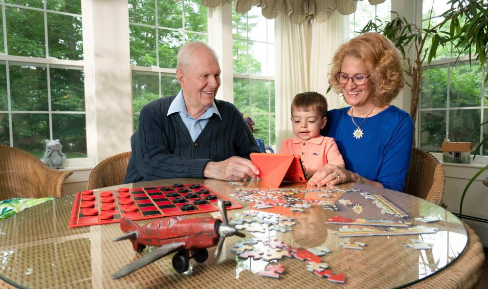 A family enjoys spending time together indoors, working on a puzzle and engaging in playtime activities.