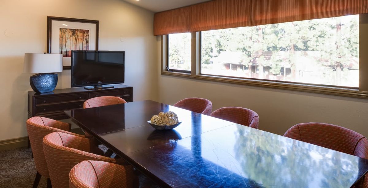 A meeting room with a large table, several chairs, and a television.