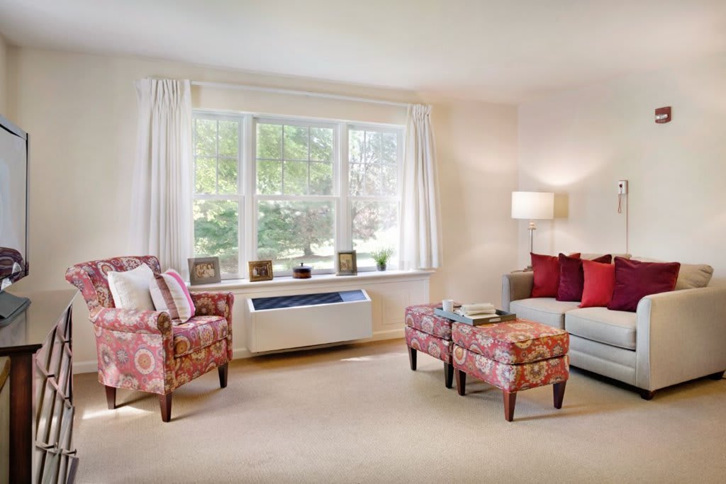 A cozy living room with colorful armchairs, a sofa, and a large window.