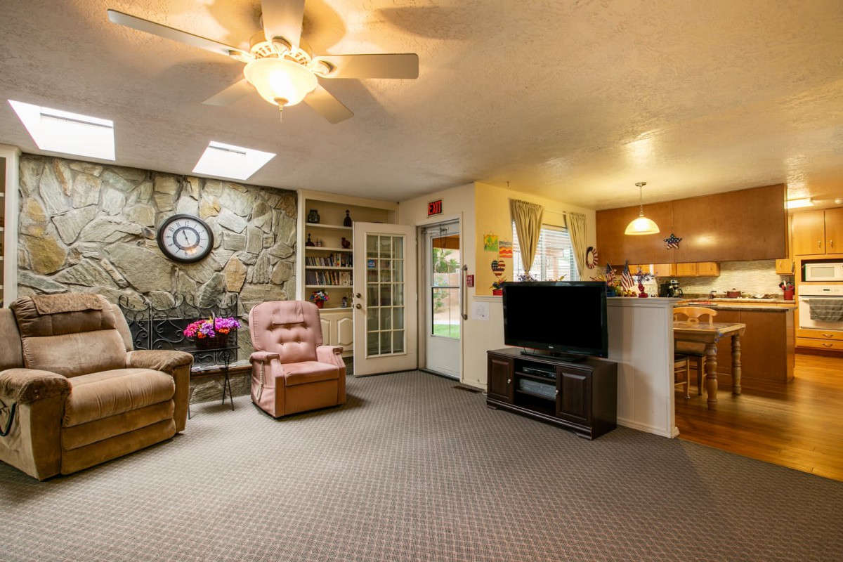 Cozy living room with an armchair, television, and ceiling fan.