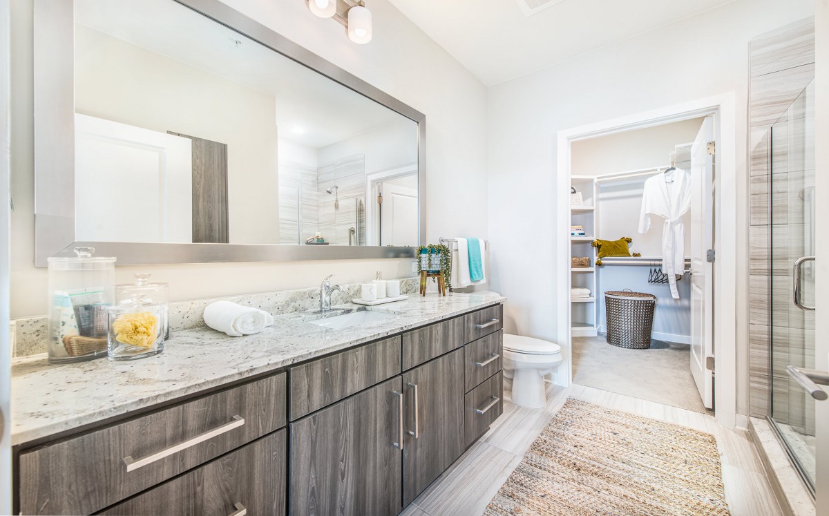 A modern bathroom featuring a large mirror, stylish cabinetry, and a clean, bright aesthetic.
